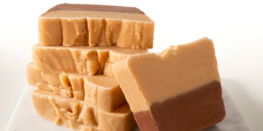 Stacked pieces of creamy fudge on a white surface.