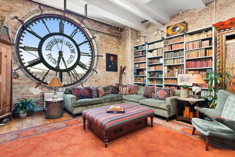 An eclectic living room inside a clock tower with brick walls and a large central clock face window.