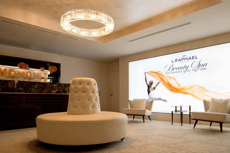 Interior of L.RAPHAEL Beauty Spa at Four Seasons Hotel New York with elegant furnishings and a large promotional wall banner.