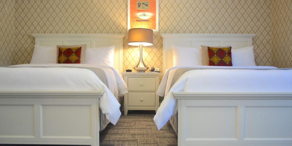 Twin beds with white linens in a hotel room with elegant, subtle decor.