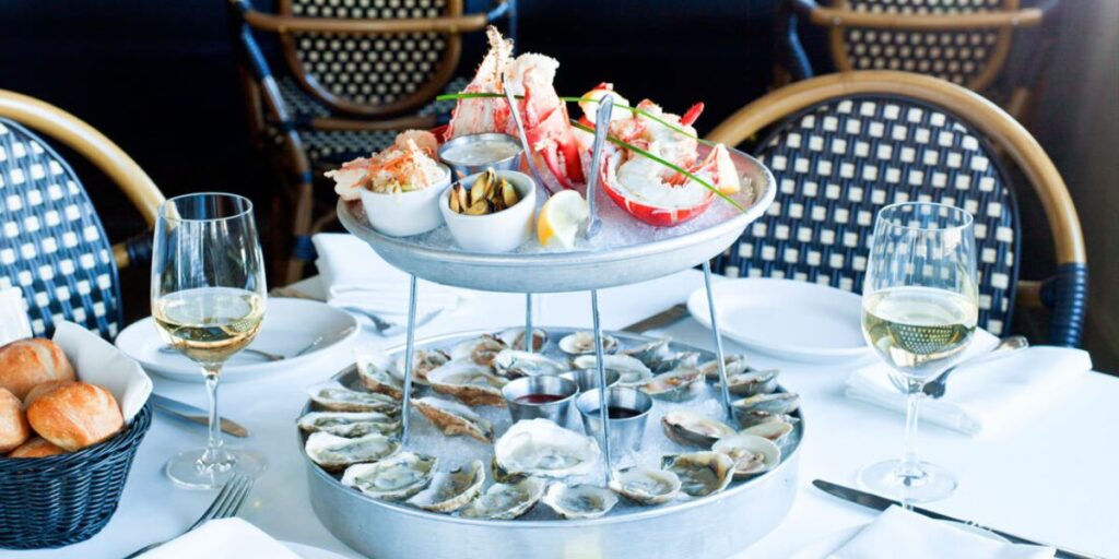 Elegant seafood tower with oysters and crab legs paired with white wine at an upscale restaurant.