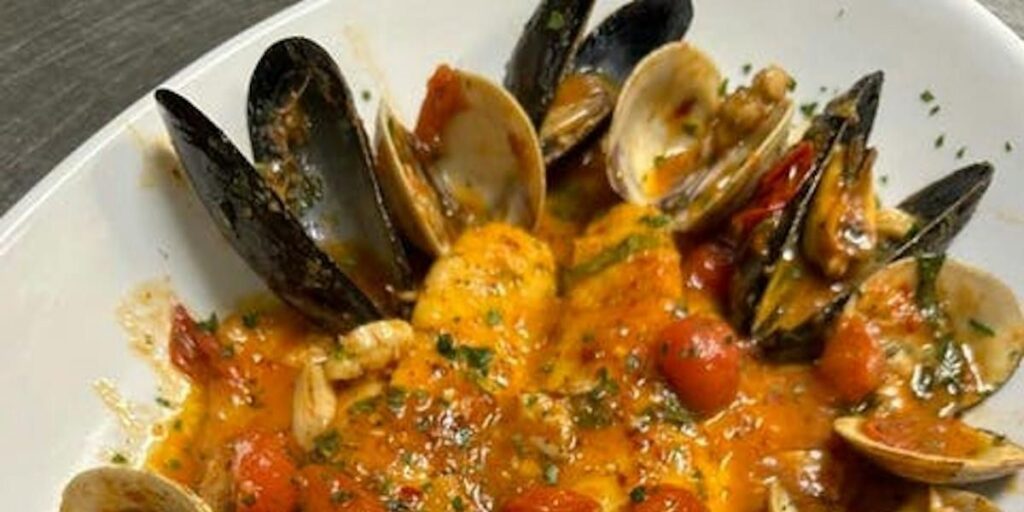 A seafood dish with mussels, clams, and shrimp in a rich tomato sauce.