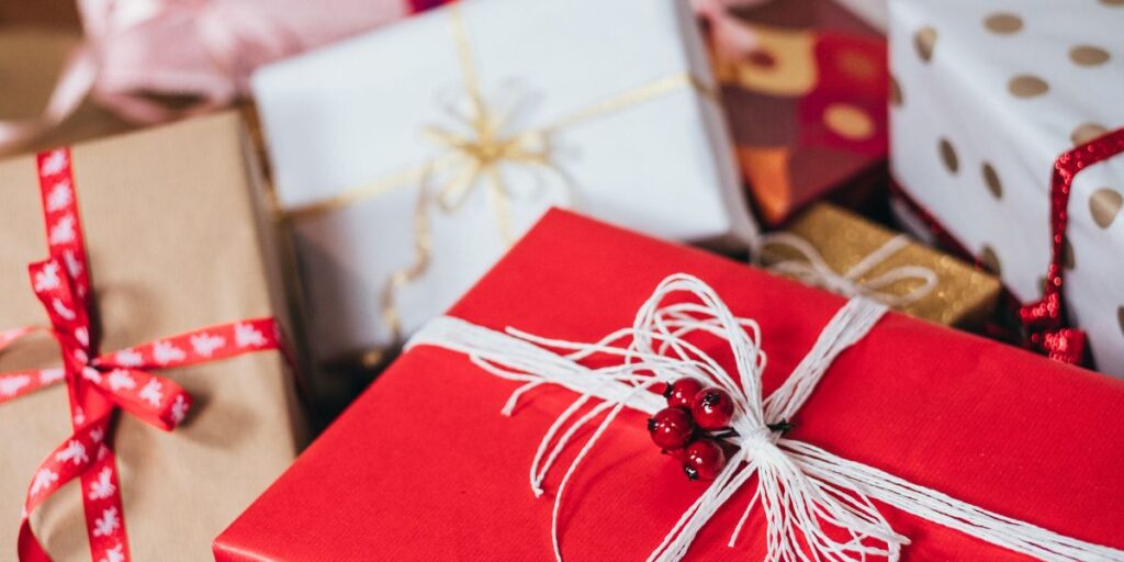 Assorted wrapped gifts with ribbons and a holly decoration on a red present.