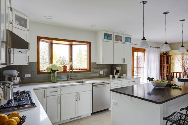 Bright kitchen with white cabinetry, modern appliances, and a wooden-framed window.