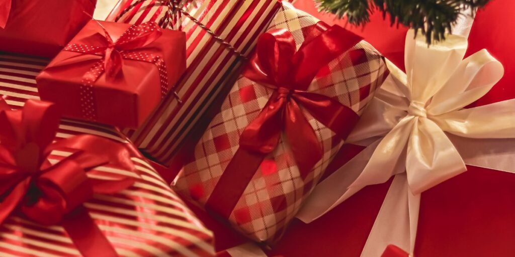 Christmas gifts wrapped in striped and checkered patterns with bold red ribbons.
