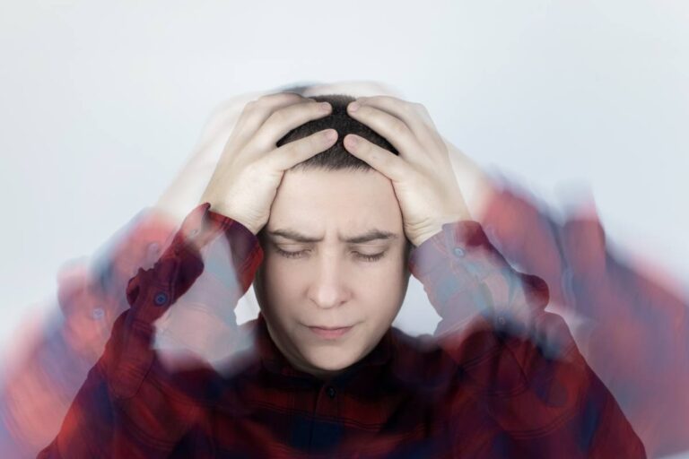 A person experiencing a migraine or headache, with hands on temples and a blurred motion effect around the head.