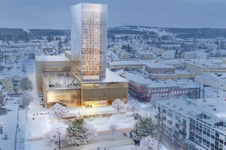 A modern cultural center with illuminated glass tower during winter evening in a snow-covered city.
