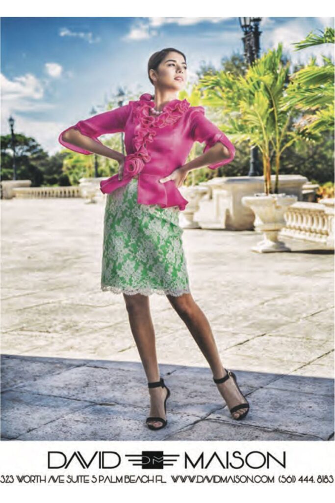 A woman models a vibrant pink blouse with ruffle detailing and a light green lace skirt in an elegant outdoor setting.