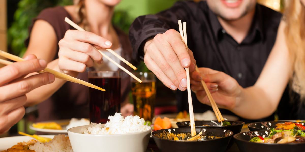 People using chopsticks while eating at a local Asian restaurant in Boca Raton, Florida