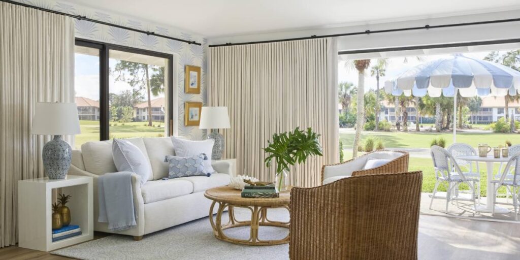 A well-appointed living room with a view of a golf course, showcasing coastal-inspired interior design with ample natural light.