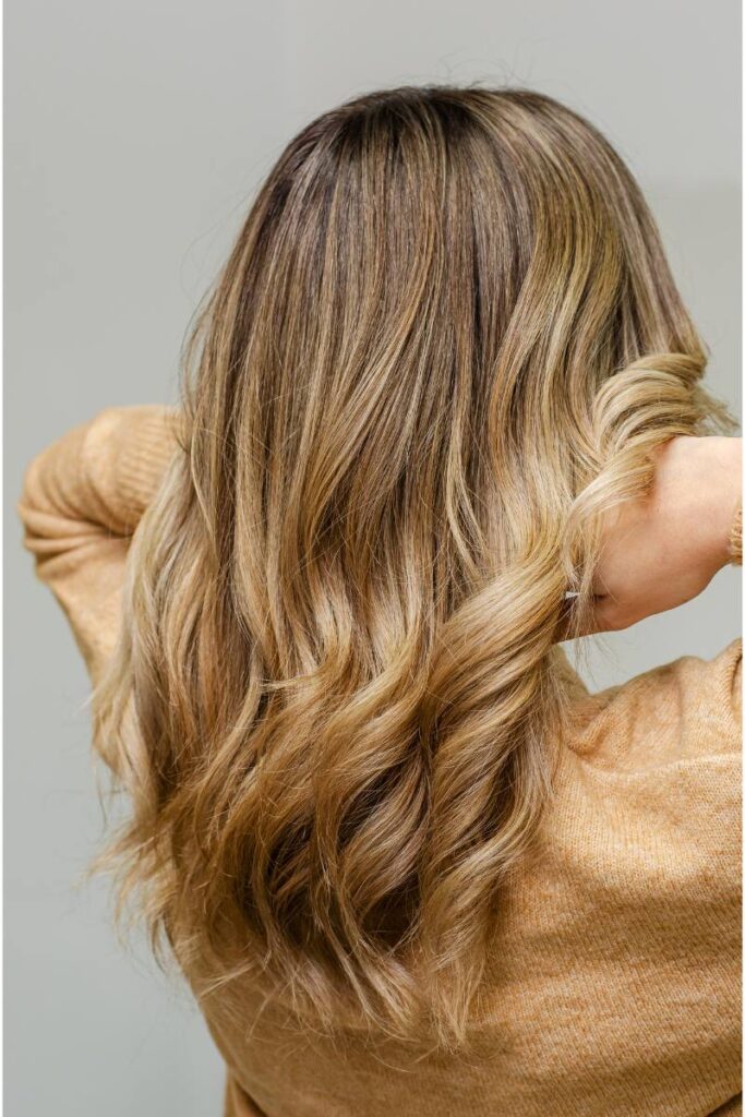 A woman from the back, showing off her wavy balayage hairstyle.