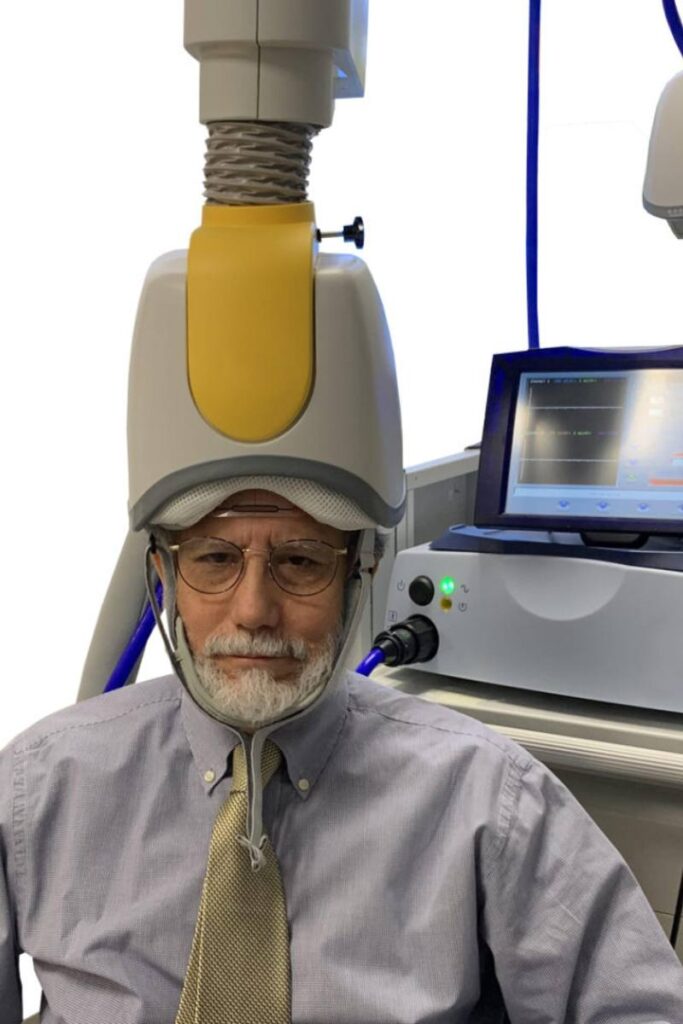 A man undergoing a deep transcranial magnetic stimulation (dTMS) therapy session.