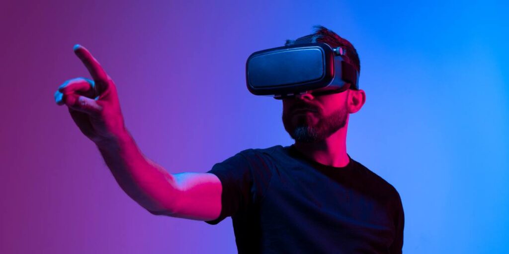 Man with beard wearing virtual reality headset, gesturing with his hand in a virtual environment with a vibrant purple and blue backdrop.