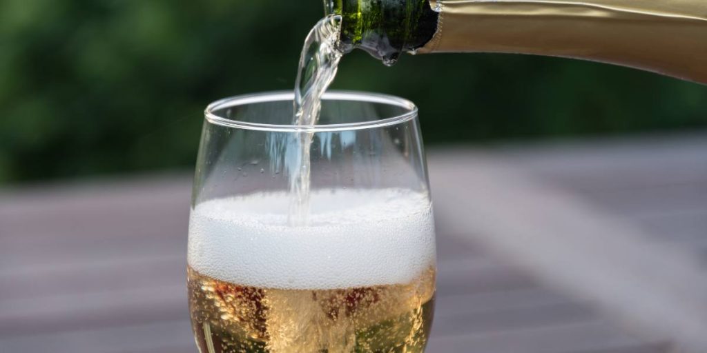 Sparkling wine being poured into a glass, capturing the effervescence and light golden hue.